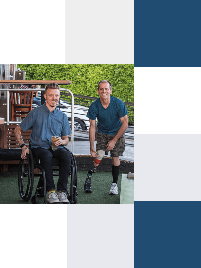 Two men with one in a wheelchair and the other is holding a prosthetic leg.